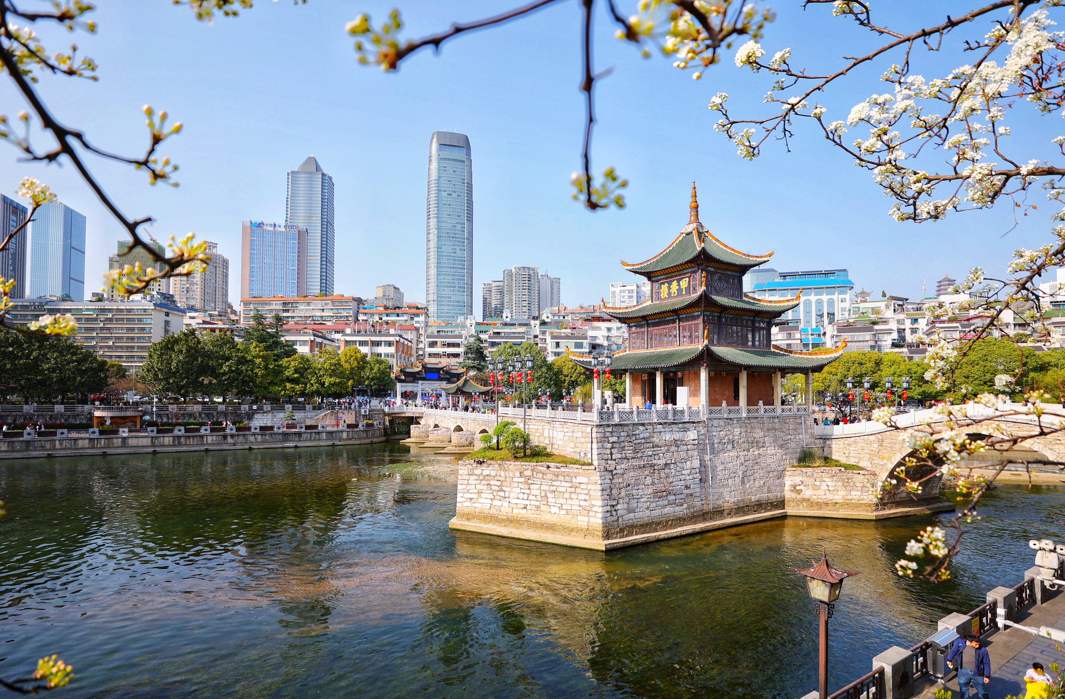 3月19日,游客在甲秀楼游玩赏景。 最近,有网友发现一处欣赏甲秀楼风光的全新角度:从位于箭道街一侧的南明河岸边茶馆看去,甲秀楼半掩于盛开的李花中,加之清澈见底的南明河水,洁白的岸边李花,悦耳的鸟鸣,空中自由飞翔的白鹭,使甲秀楼呈现出一种有别于常规视觉的魅力和美感来,令人更加赏心悦目,美不胜收,美妙的欣赏角度令不少游客纷纷前往打卡拍照。